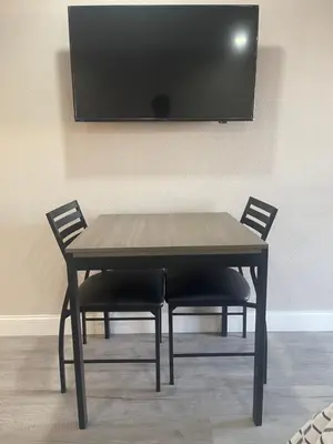 a wooden table with two chairs and a television on a wall at Town House Motel in Sanger