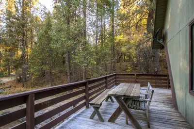 a wooden table and chairs on a wooden deck at Yosemite's Creekside Birdhouse in Wawona