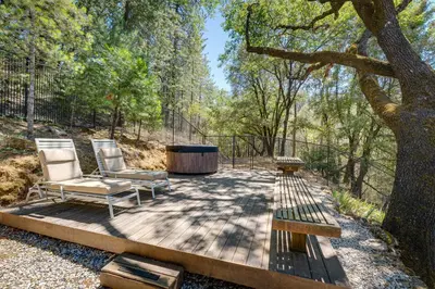 two chairs and a table on a wooden deck with a tree at Meadow Vista Mountain Escape with River Views! in Meadow Vista