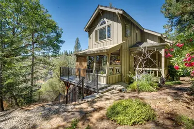 a green house with a porch and a balcony at Meadow Vista Mountain Escape with River Views! in Meadow Vista