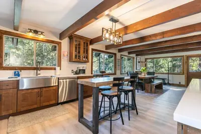 a kitchen with wooden cabinets and a large island with bar stools at Brand New 3BDR Cabin 4 Min to Ski Resort and Beach in Tahoma