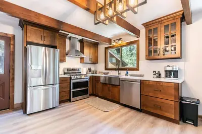 a kitchen with wooden cabinets and stainless steel appliances at Brand New 3BDR Cabin 4 Min to Ski Resort and Beach in Tahoma