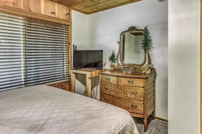 a bedroom with a bed and a mirror on a dresser at 3 Mi to Shaver Lake Cozy Bears Hideaway Cabin! in Shaver Lake