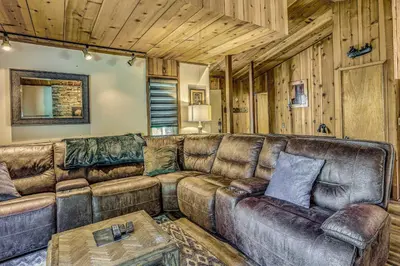 a living room with a leather couch and a table at 3 Mi to Shaver Lake Cozy Bears Hideaway Cabin! in Shaver Lake