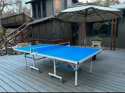 a ping pong table on a deck with an umbrella at Magical River House ! 10 min to SNP park entrance in Three Rivers