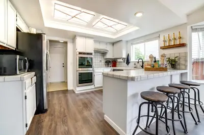 a kitchen with white cabinets and a counter with stools at Pet-Friendly Home with Hot Tub! 6 Mi to Dtwn Reno in Reno