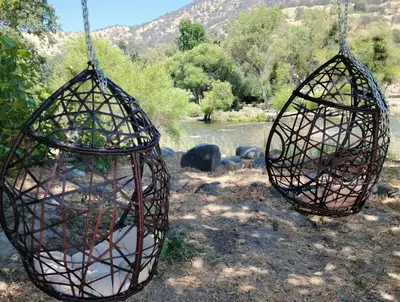 two bird cages hanging from a chain near a river at Oasis Riverfront House -10 min to Sequoia in Three Rivers