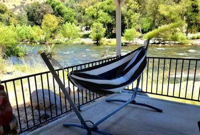 a hammock sitting on a porch next to a river at Oasis Riverfront House -10 min to Sequoia in Three Rivers