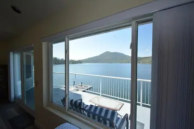a room with a large window with a view of the water at Beautiful Lakefront Home Spectacular View - Herrera in Bass Lake