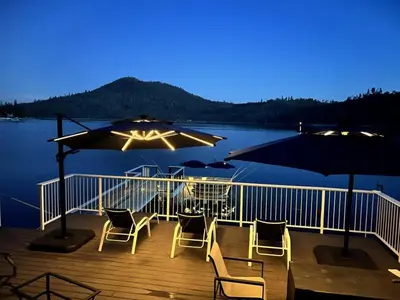 a deck with chairs and tables and umbrellas at Beautiful Lakefront Home Spectacular View - Herrera in Bass Lake