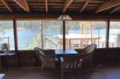 a table and chairs in a room with a view of the water at Charming 1927 Lake Front Home - Hargrave in Bass Lake