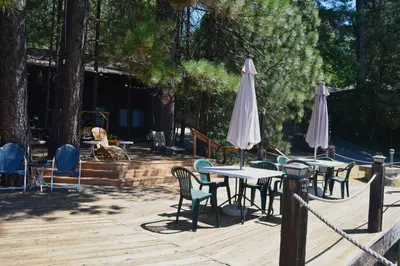 a group of tables and chairs with umbrellas on a deck at Charming 1927 Lake Front Home - Hargrave in Bass Lake