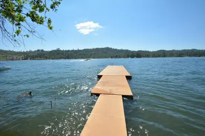 a dock on a lake with a person in the water at Dupzyk Lake Front Reduced Nightly Rate in Bass Lake