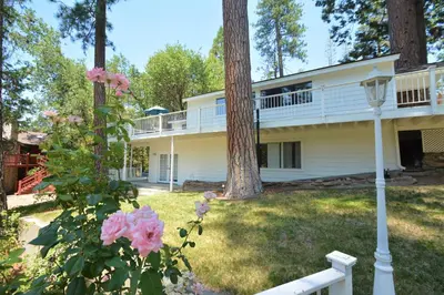 a large white house with trees and pink roses at O'Hara Lake View in Bass Lake