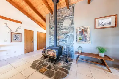 a stone fireplace in a living room with a wooden ceiling at Yosemite Cowboy Cabin in Oakhurst