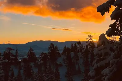 a sunset in the mountains with trees and snow at Sunrise Serenity at Tahoe Village in Stateline