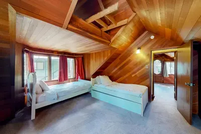 two beds in a room with wooden walls at Sierra Secret in Soda Springs