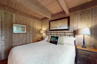 a bedroom with a white bed and wooden walls at Fernwood in Shaver Lake