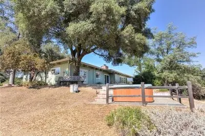 a house with a tree and a fence in front of it at Black Bear Haven Hot tub Pool table BBQ Darts in Oakhurst