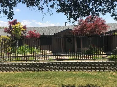 a black fence with a stone bench in a yard at Crane Suite Hot Tub Bbq King Bed- Sleeps 4 in Ahwahnee