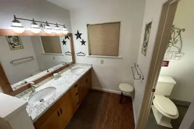 a bathroom with two sinks and a toilet and a mirror at Creekside Dream Game Room Sleeps 12 bbq near town in Oakhurst