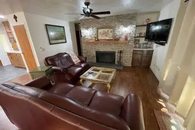 a living room with a leather couch and a fireplace at Creekside Dream Game Room Sleeps 12 bbq near town in Oakhurst