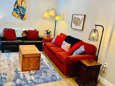 a living room with a red couch and a table at Eagle Nest River Views Hot Tub Games Sleeps 6 in Ahwahnee