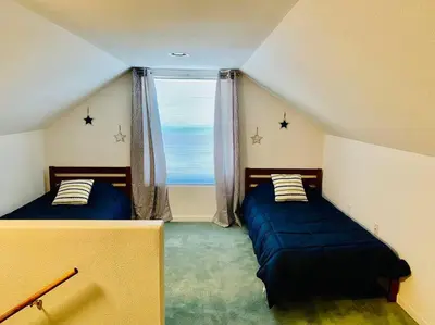 a attic room with two beds and a window at Eagle Nest River Views Hot Tub Games Sleeps 6 in Ahwahnee