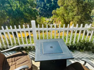 a table with a laptop on it next to a white fence at Happy Hedgehog River Views Hot Tub Private in Ahwahnee