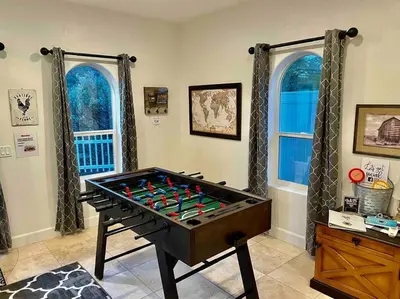 a room with a foosball table in front of two windows at The Funky Chicken Hot Tub BBQ SLEEPS 4 in Ahwahnee