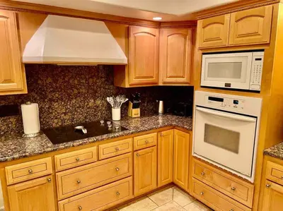 a kitchen with wooden cabinets and a white microwave at Peacock Suite Hot Tub Sleeps up to 4 Bbq in Ahwahnee