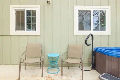 two chairs and a tub in a room with two windows at Raccoon Hideout Hot Tub BBQ Arcade Darts in Oakhurst