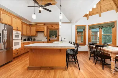 a kitchen with wooden cabinets and a table with chairs at Yosemite Villa - log cabin with spectacular views & stargazing in Mariposa