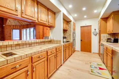 a large kitchen with wooden cabinets and wooden floors at 5 Mi to Donner Lake Cabin with Deck and Pool Access! in Truckee