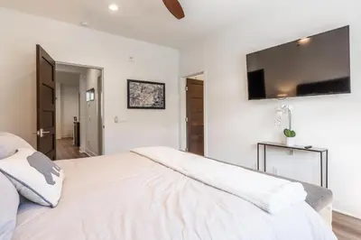 a white bedroom with a large bed and a flat screen tv at Creekhouse 1583 in Mammoth Lakes