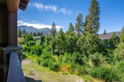 a view from the porch of a house with trees and mountains at Creekhouse 1583 in Mammoth Lakes