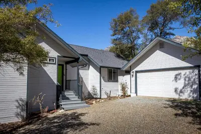 a white house with a garage at **Kaweah River House** - 1/2 Mile to Sequoia Park in Three Rivers