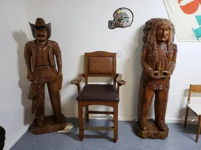 two wooden statues and a chair next to a wall at Sierra River House 5 min to Sequoia Park Entrance in Three Rivers