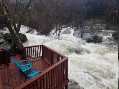 two blue chairs sitting on a deck next to a river at Sequoia River House, close to SNP, 2 Decks on Amazing River on 7acres in Three Rivers