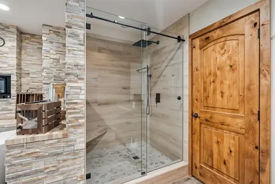 a shower in a bathroom with a wooden door at Water's Edge - Gorgeous Water Views! home in Groveland
