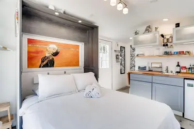 a bedroom with a white bed and a kitchen at TINY ART HOUSE near the beat in Sacramento
