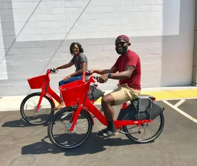 a man and a woman riding on a red bike at TINY ART HOUSE near the beat in Sacramento