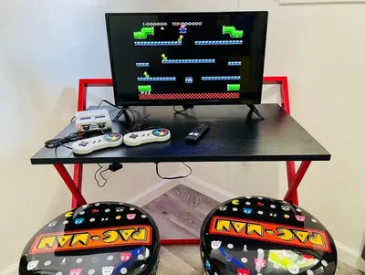 a desk with a computer monitor and two controllers at Artists Bungalow ARCADE King Beds near the beat in Sacramento