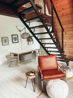 a living room with a staircase with a chair and a table at Mid Century Modern Cabin - The Tahoe A-Frame in Homewood