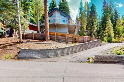 a house on a hill with a fence in front of it at Zen Amongst the Trees in Truckee