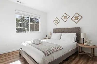 a white bedroom with a large bed and a window at Brookside Cottage in Mariposa