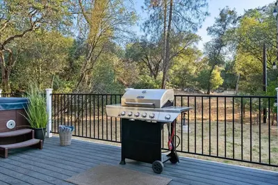 a grill sitting on a deck next to a fence at Brookside Cottage in Mariposa
