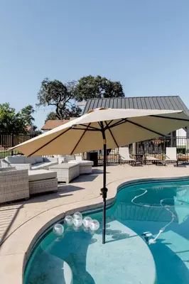 a pool with an umbrella next to a swimming pool at Beautiful spacious guest home in Roseville