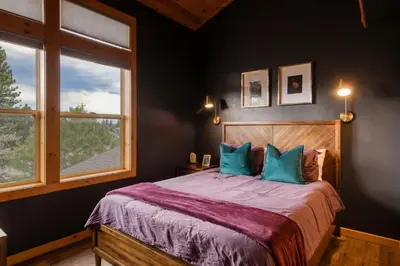a bedroom with a bed with blue pillows and a window at The Modern Moose Lodge in Truckee