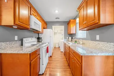 a kitchen with wooden cabinets and white appliances at Longer Stays for Travelers- Apt Blocks from Hospital, Downtown in Visalia